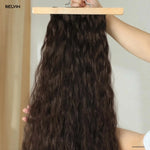 Dark brown wavy human hair extensions clip in set displayed on wooden board for added volume and length