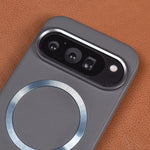 A close-up of a dark gray textured phone case with a metallic silver MagSafe ring and a camera cutout, shown on a brown textured leather background.
